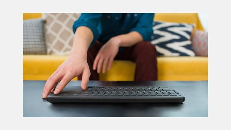  Microsoft All-in-One Media Keyboard – mężczyzna korzystający z klawiatury na kanapie
